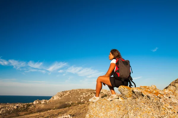 Mujer excursionista se sienta en la playa montaña roca —  Fotos de Stock