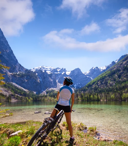 Młoda kobieta, jazda na rowerze obok alpejskiego jeziora — Zdjęcie stockowe