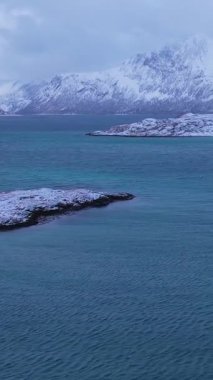 Norveç 'in Sommaroy adasında, güneşli kış mevsiminde, karla kaplı dağ zeminli bir kumsal çevresindeki hava manzarası