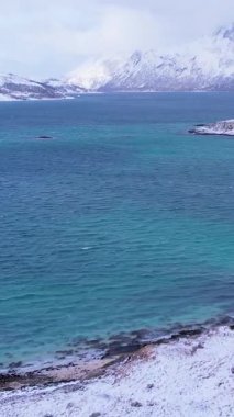 Norveç 'in Sommaroy adasında, güneşli kış mevsiminde, karla kaplı dağ zeminli bir kumsal çevresindeki hava manzarası