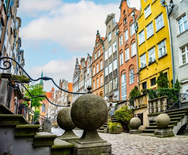 Gdansks Mariacka Caddesi ikonik mimarisini, kaldırım taşı yollarını ve canlı cephelerini sergiliyor. Tarih ve kültür öğeleri bu resimli şehir sahnesinde yer alır.