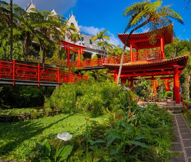 Portekiz 'in Madeira adasında popüler bir turizm merkezi olan Funchal şehrinin üzerinde kırmızı pagoda gölleri ve geleneksel binaları olan Monte Palace tropikal bahçesi.