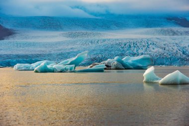 Fjallsarlon buzul gölleri sakin sularda yüzen buzdağlarını sergiliyor. Büyük buzul zeminine vuran alacakaranlık ışığını yansıtıyor. İzlanda 'da ikonik bir konum
