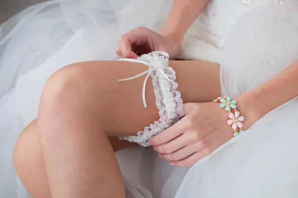 Bride putting a wedding garter on her leg — Stock Photo, Image