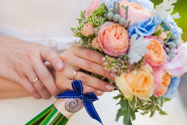 Las manos de la novia y el novio en el fondo de un primer ramo de boda — Foto de Stock