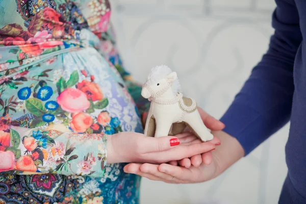 Soft toy "horse" in the hands of the husband and pregnant wife closeup — Stock Photo, Image