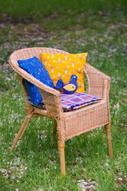 Wicker chair with cushions and a plaid close-up on background of grass in the garden. clipart