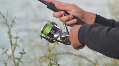 Yakından bir balıkçının elleri kunduzun veya gölün makarasında sallanıyor..