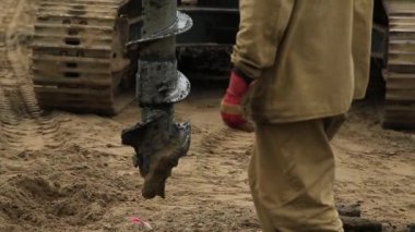 İşçi makineye matkabı doğru yere yerleştirmesinde yardımcı olur. Matkap aşağı iner.