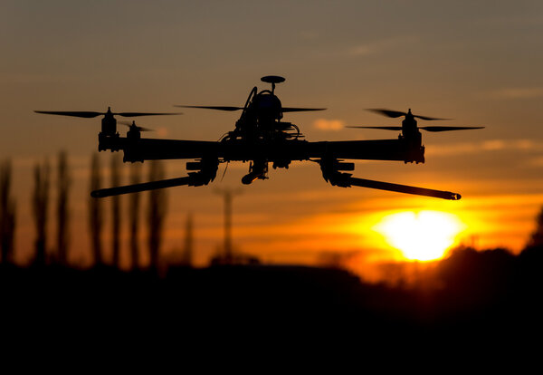 Беспилотник-гексакоптер летит на закате
