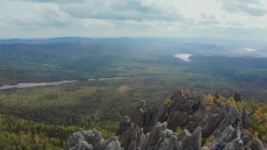 Bir adam bir kayanın üzerinde ellerini kaldırıyor.