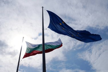  AB ve Bulgaristan 'ın bayrakları gökyüzüne karşı rüzgarda dalgalanıyor