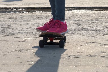 Güneşli bir günde kaykayın üstünde bir kızın bacakları