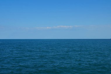 Bulutlu gökyüzü, güneşli bir günde pürüzsüz bir ufukta deniz.