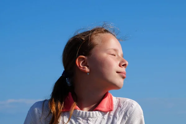 girl closed her eyes and sets her face to the sun, portrait