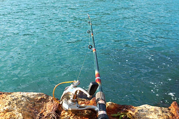 Spinning Rod Łowienia Tle Wody Morskiej Kamieni Przybrzeżnych Zbliżenie — Zdjęcie stockowe