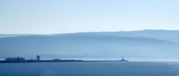 seascape, coast with a lighthouse in a blue haze.