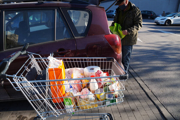 Varna, Bulgaria - November, 28, 2020: a man loads purchases from a shopping cart into a car