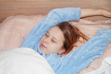 Mavi, sıcak pijamalı genç kız sabahları yatakta esniyor..