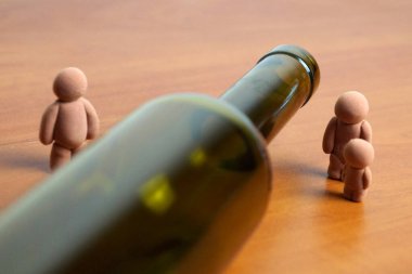 Boş şarap şişesi, çocuklu kadın ve erkek figürlerini, alkolizm ve aile kavramlarını ayırır.