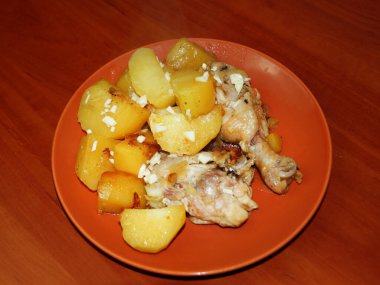 Tahta arka planda seramik tabakta tavuk ve sarımsaklı patates yahnisi..