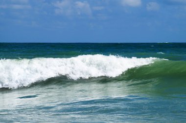 Beyaz dalgalar, deniz ufku ve bulutlu güneşli gökyüzü..