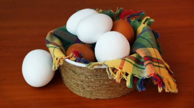 beyaz ve kahverengi yumurtalar kareli bir peçete üzerinde bir kasede ahşap bir masada.