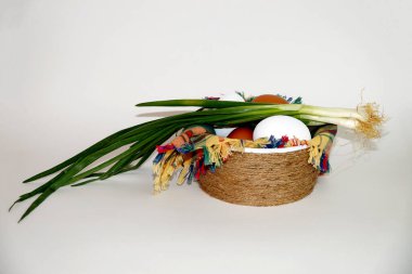 Beyaz ve kahverengi yumurtalar ve beyaz arka plandaki bir kasede kareli bir peçete üzerinde bir demet yeşil soğan..