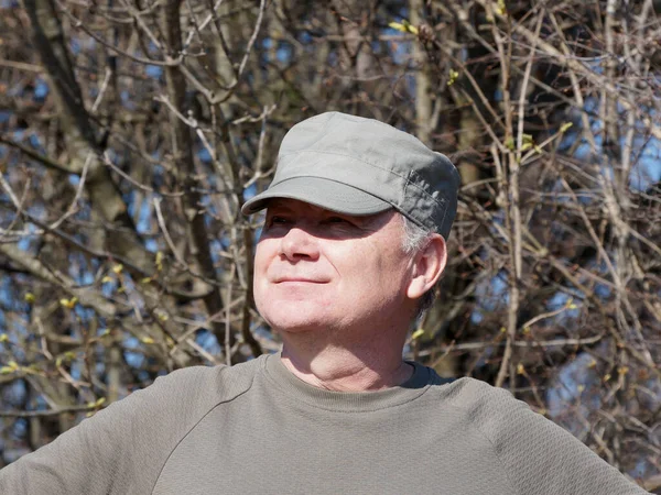 portrait of an adult smiling man in a cap on the background of nature.