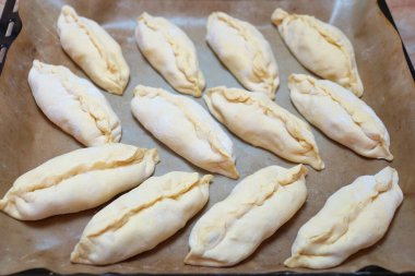 Yemek arkaplanı için fırın tepsisindeki çiğ küçük turtalar, yukarıdan görünüm