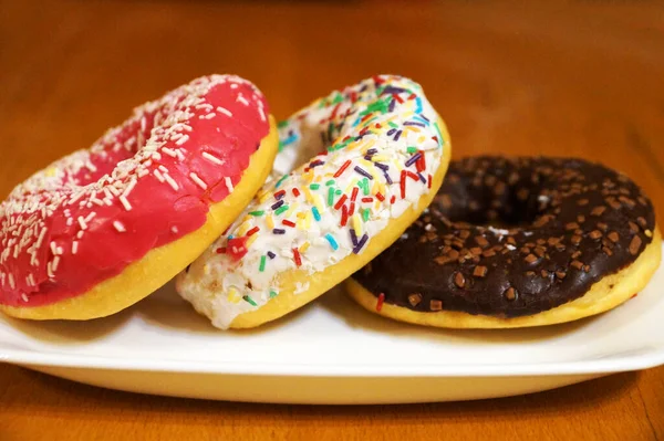 Donuts Multicoloridos Com Esmalte Uma Placa Branca Close — Fotografia de Stock