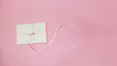 Pembe arkaplanda beyaz hediye zarfı, kopyalama alanı