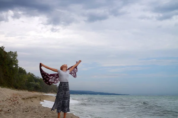 嵐の日に腕を伸ばして海岸にスカーフを振って女の子 — ストック写真