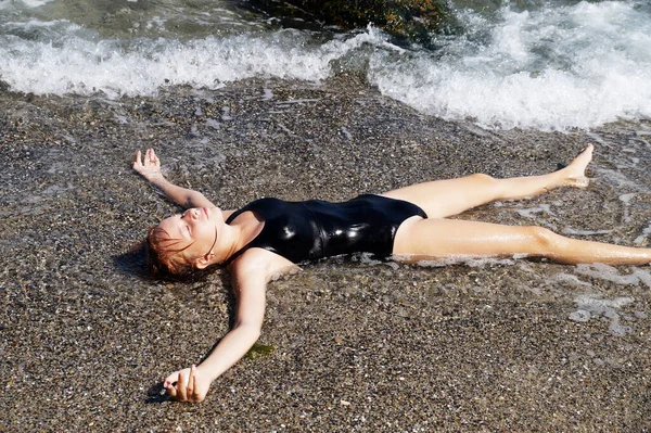 Kız sırt üstü uzanmış, kollarını deniz kıyısındaki dalgalara uzatmıştı..