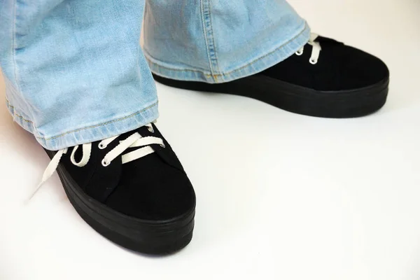 Vrouwelijke Benen Blauwe Jeans Zwarte Sneakers Een Witte Achtergrond — Stockfoto