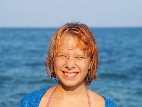 笑顔の10代の少女は海を背景に太陽から目をねじ込み — ストック写真
