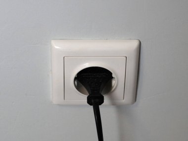 Beyaz bir prize takılmış siyah bir kabloyu yakından çek.