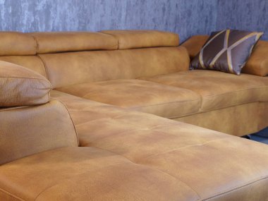 Modern ev dekorunu ve rahat yaşam alanını sergilemek için yumuşak yastıkları ve zarif dokusu olan modern kahverengi deri kanepe..