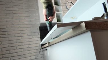 Kablosuz matkapla dolap kapısında bir delik açmak..