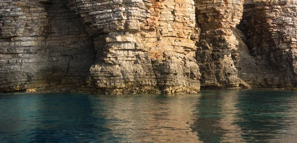 समुद्र चट्टान, परतदार चट्टानों और पत्थरों को टर्किज़ ब्लू सागर पानी के साथ बंद करें — स्टॉक फ़ोटो, इमेज