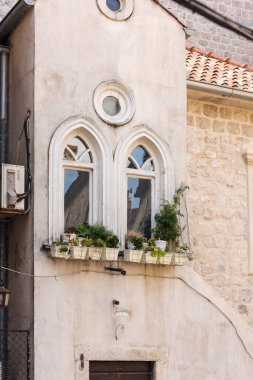 Güzel camları ve saksı bitkileri olan eski bir evin sokak manzarası. Kotor, Karadağ.