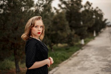 Siyah bir benekli elbise içinde, elinde eski bir valizle genç ve güzel bir kız..