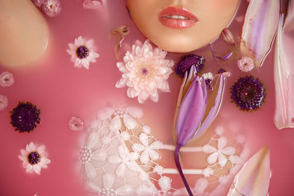 Beautiful portrait of a woman with flowers and petals in rose water. Facial cosmetics that moisturize the skin.