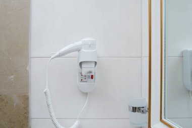 Otel banyosunun duvarında saç kurutma makinesi var..