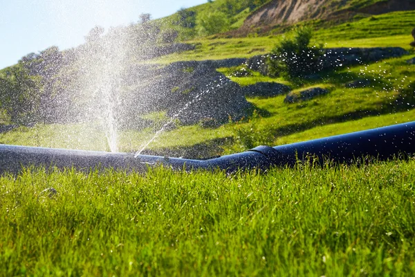 Water splashes under pressure from the damaged pipe.