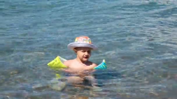Un niño pequeño aprende a nadar en el mar abierto, en la naturaleza — Vídeos de Stock