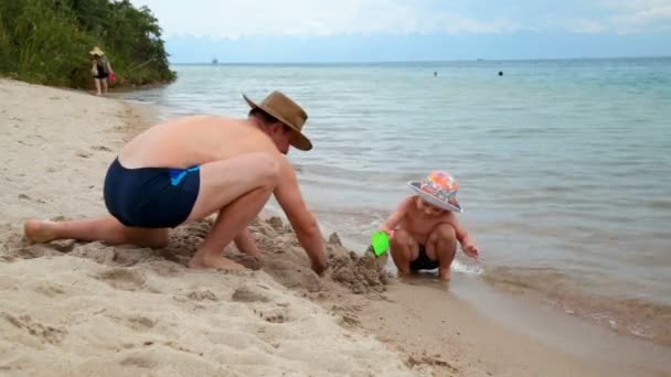 Πατέρας με μικρό γιο παίζει με άμμο στην παραλία — Αρχείο Βίντεο
