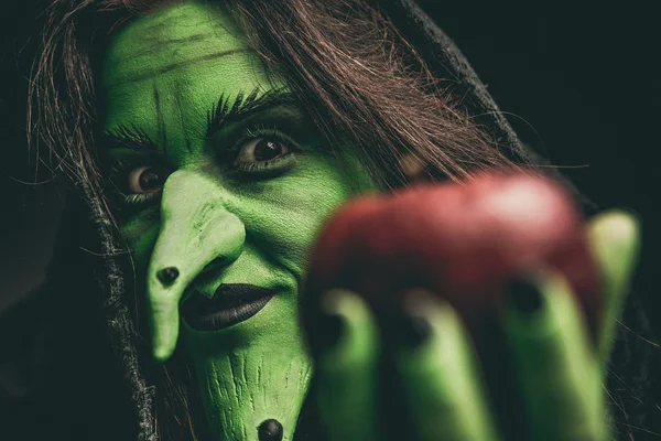 Злая ведьма смотрит в камеру с красным яблоком — стоковое фото