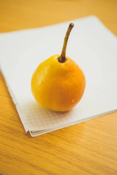 Mogna gula päron frukt på en vit anteckningsbok papper i en bur — Stockfoto