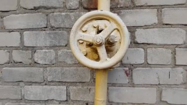 Binanın duvarındaki boru hattında sarı gaz vanası var..